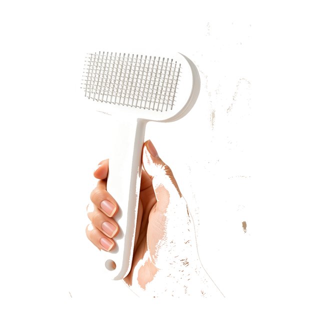 White self-cleaning slicker brush with fine metal bristles and hanging hole, held in hand.